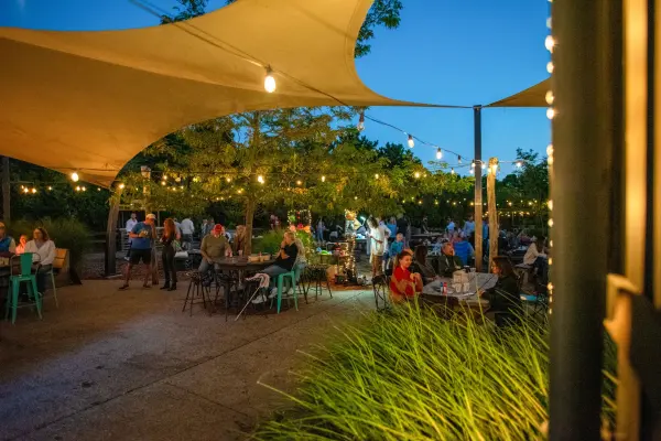 String lights and sail shades over Noman's garden seating on a summer evening.