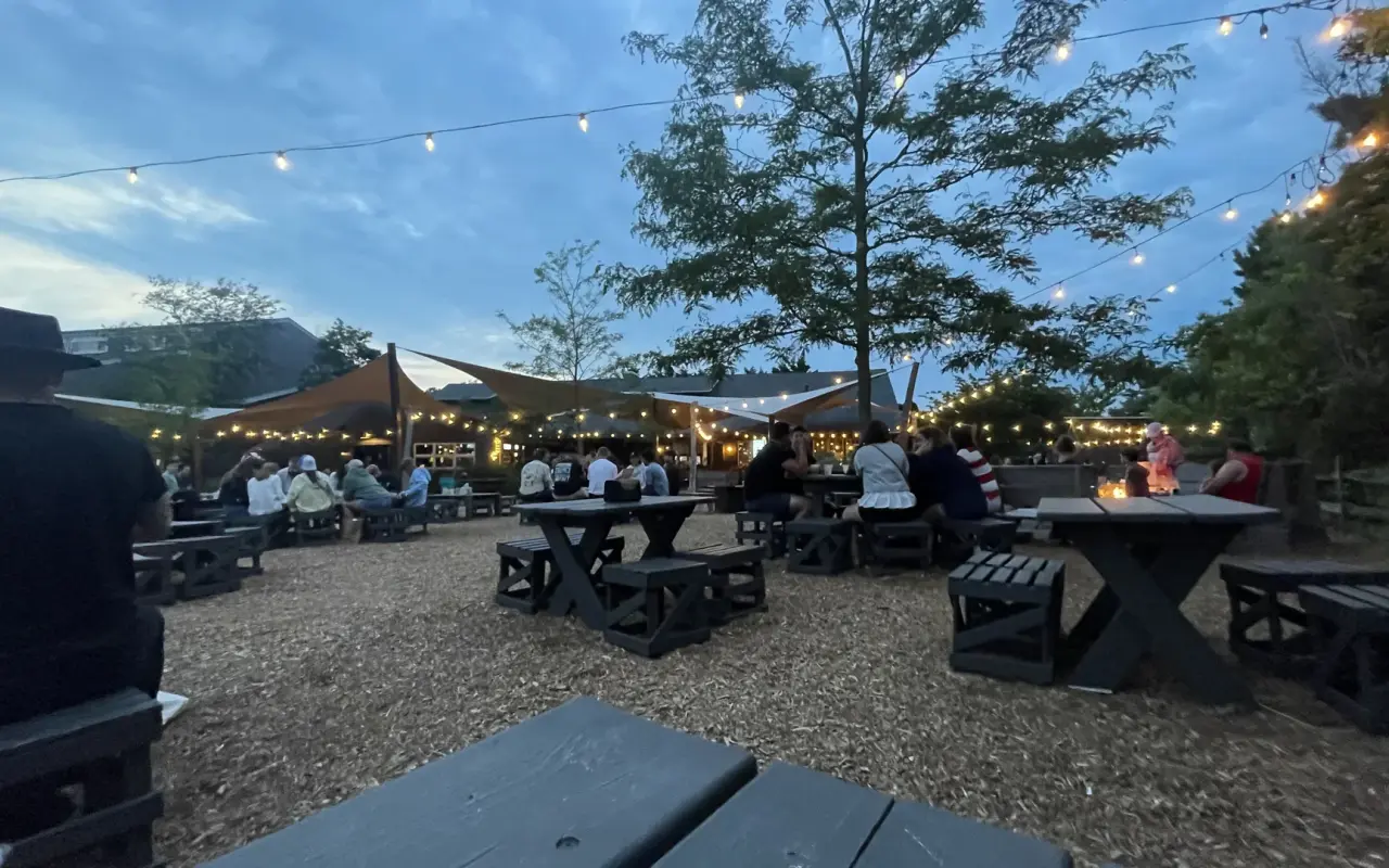 Picnic tables at Nomans at twilight with string lights overhead