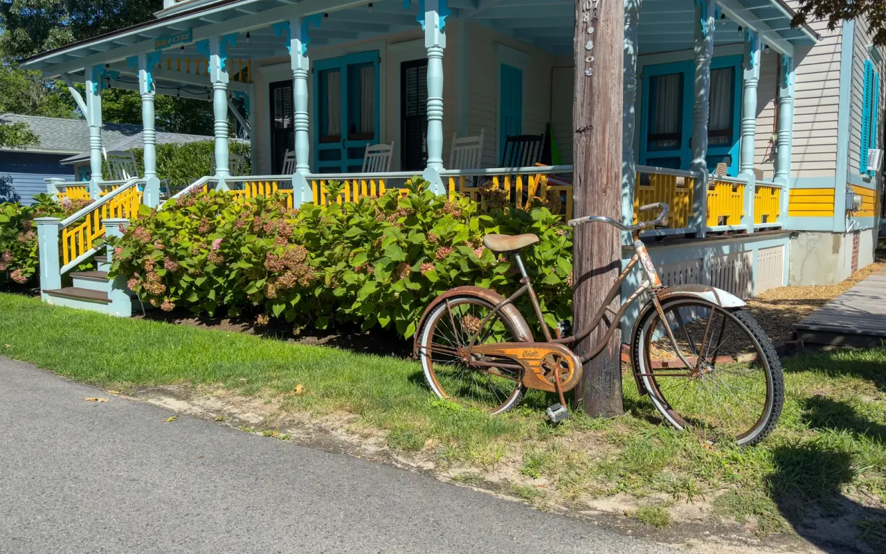 Vintage bicycle leaning on a utility pole in front of a turquoise and yellow gingerbread cottage in Oak Bluffs
