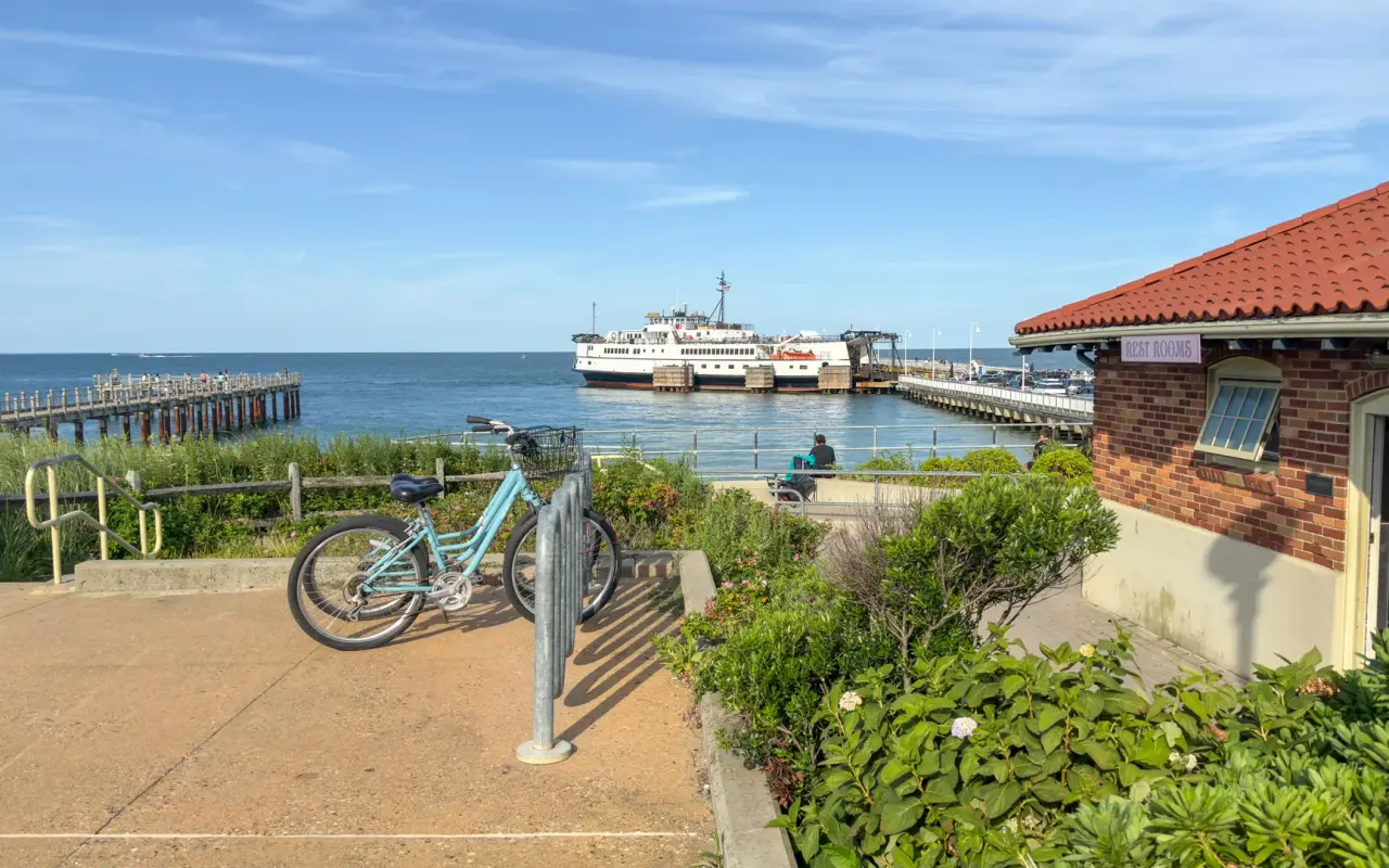 A light blue bicycle at a rack near the Oak Bluffs ferry wharf, with a Steamship ferry docked in the background