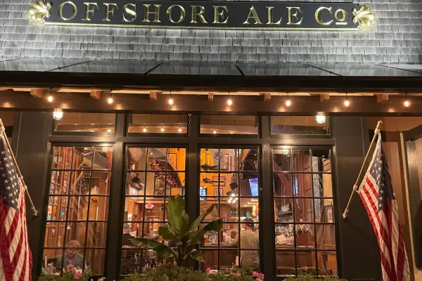 Offshore Ale Co. entrance framed by American flags at night