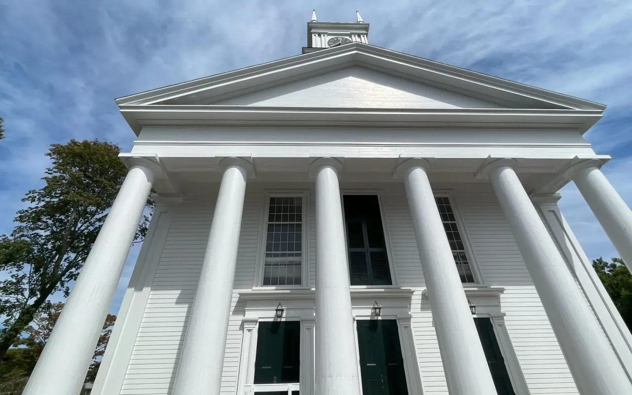 Looking up at the white Doric columns and pediment of the Old Whaling Church in Edgartown
