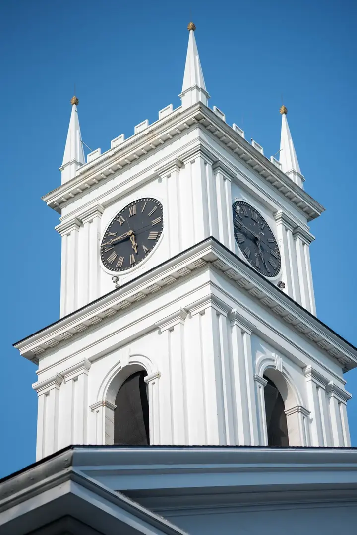 The white clock tower and spires of the Old Whaling Church in Edgartown against a deep blue sky