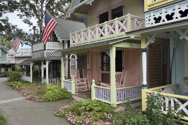 Pink and green cottage with rockers and string lights, yellow neighbour with heart cutouts