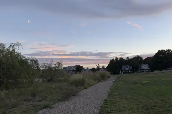 A pond-side path in Oak Bluffs at dusk with a half moon up