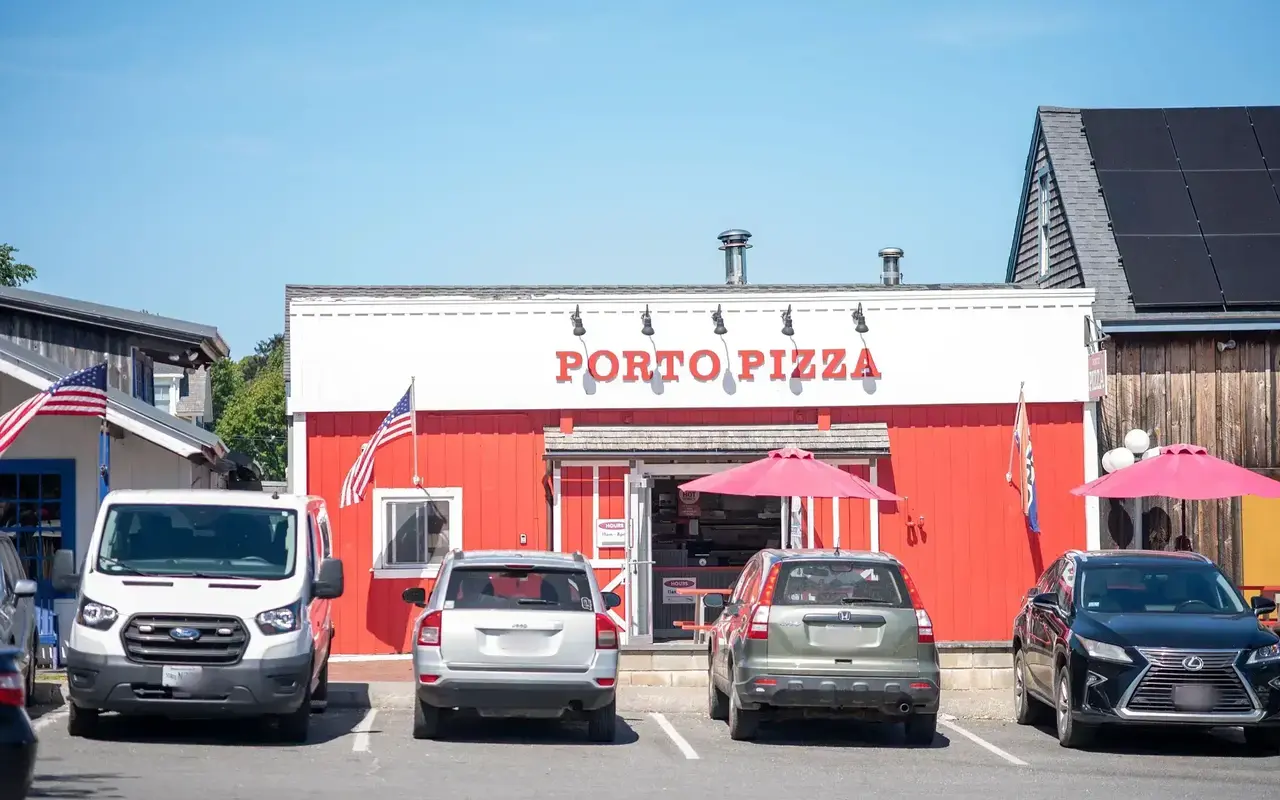 Porto Pizza, a red building with white trim and red umbrellas, cars parked in front