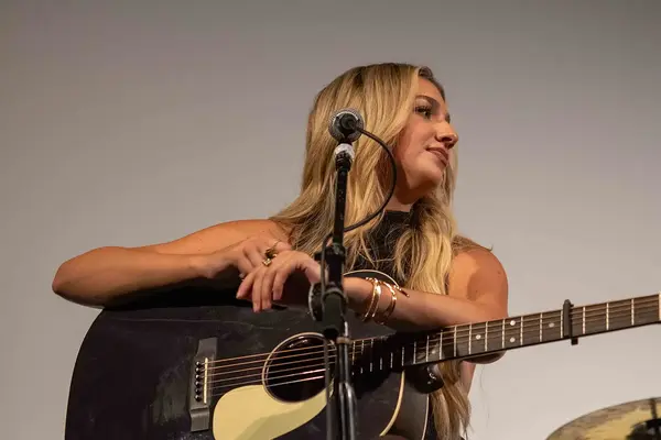 Presley Tennant, arms folded over a black guitar, listening to the next writer