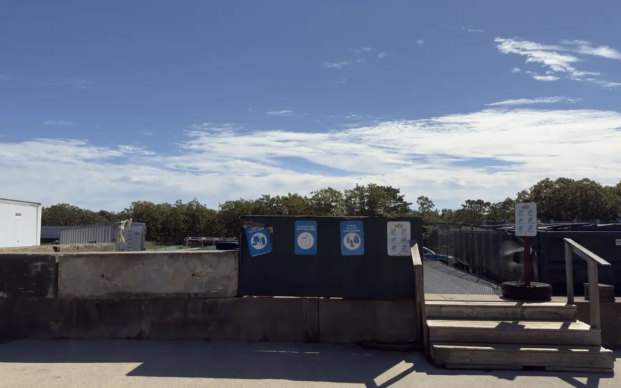 The raised recycling platform at the Edgartown transfer station, with blue bin signs, a list of what stays out and wooden steps