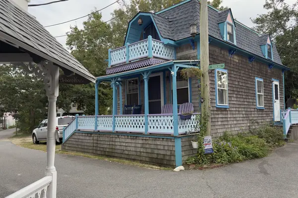 A cottage with turquoise and lavender trim on Rustic Avenue, mansard roof and purple chairs