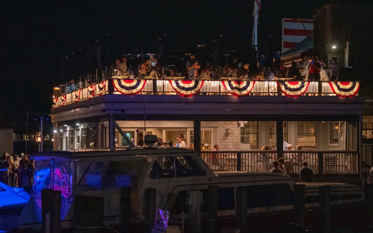 The Seafood Shanty restaurant on Edgartown harbor lit at night with red, white and blue bunting