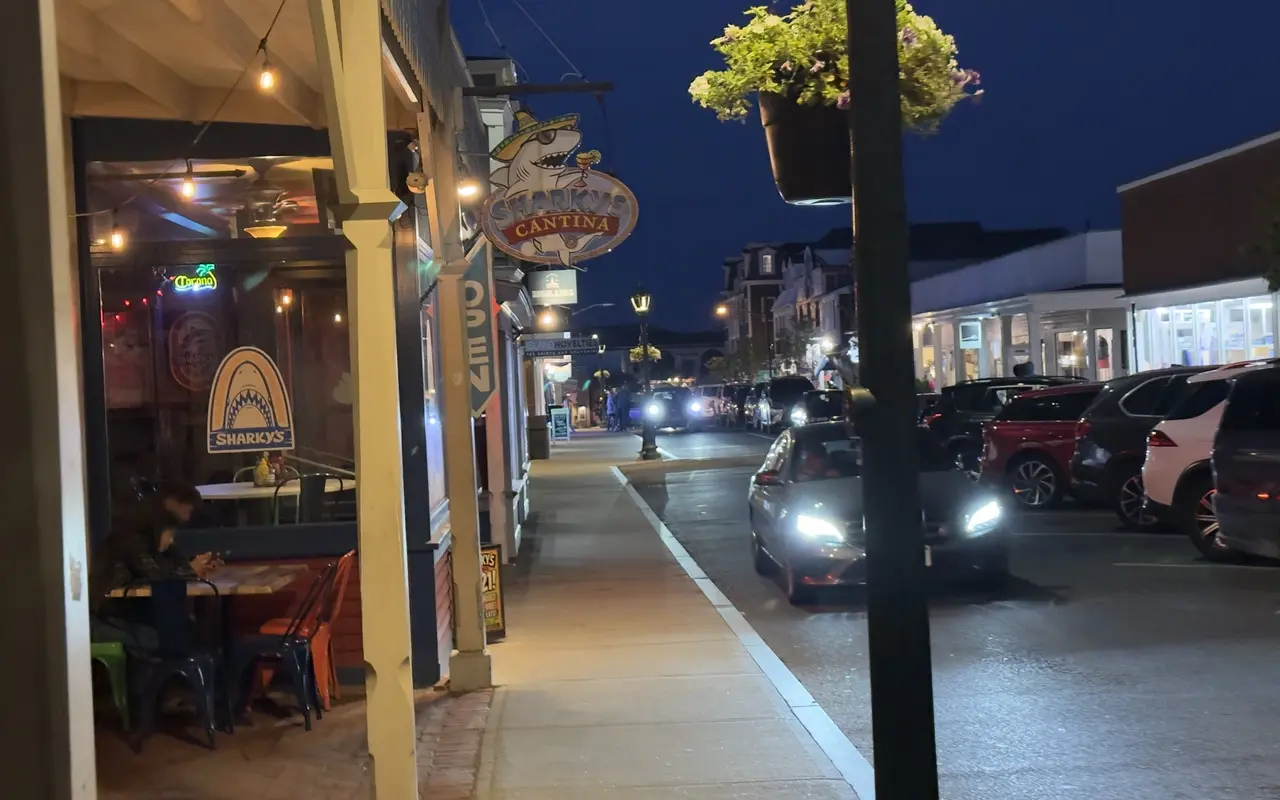 Sharky's Cantina on Circuit Avenue in Oak Bluffs at night, the shark sign lit and a diner at a window table