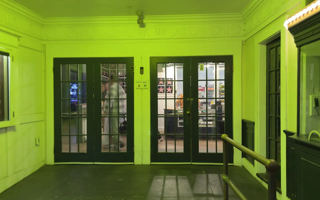 The lobby of the Strand Theatre in Oak Bluffs lit green, with French doors to the concession stand and the box office window on the right