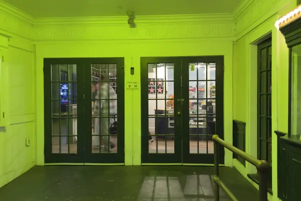 The Strand lobby under its green light, the box office window on the right