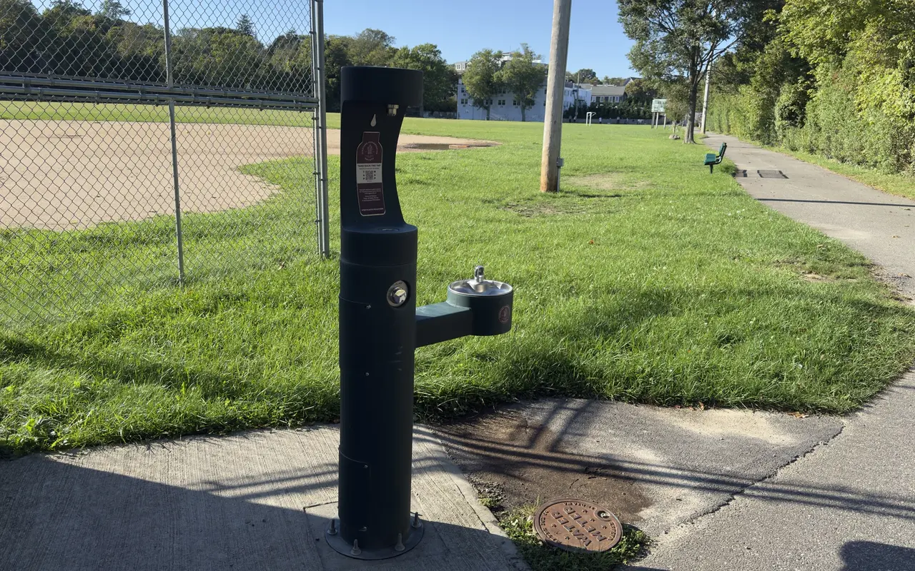 A green bottle-refill station and drinking fountain on the path beside the ball field at Veterans Memorial Park in Vineyard Haven