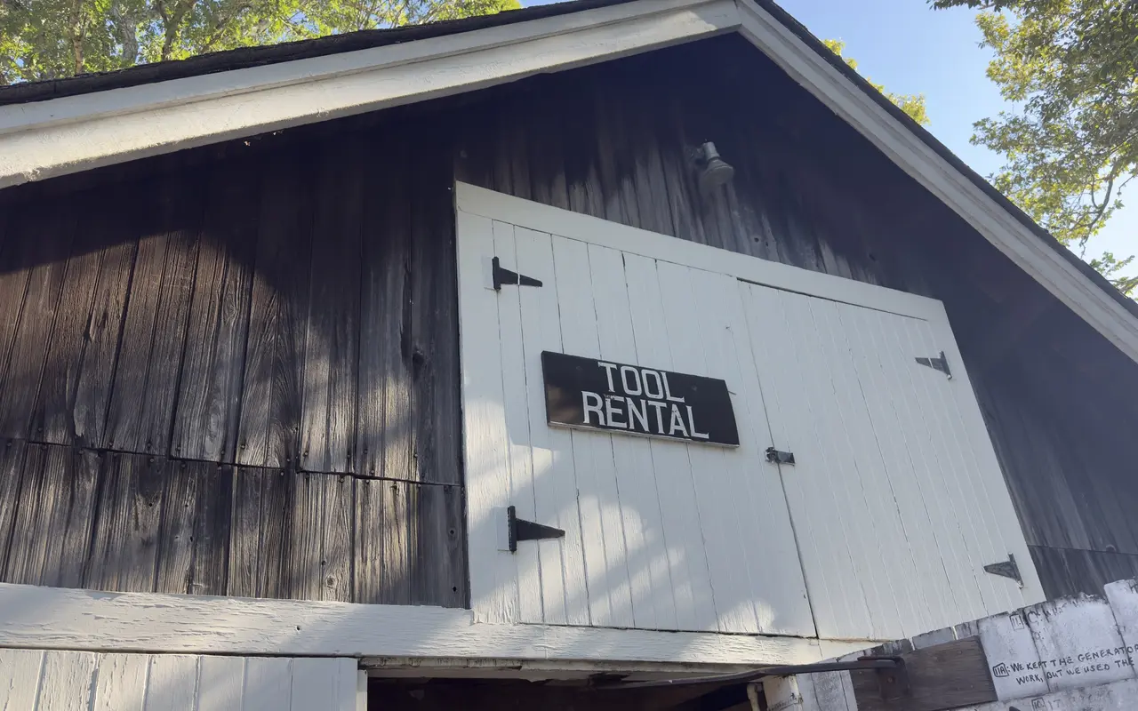 The weathered gable of the Tilton tool rental barn in Vineyard Haven with a black and white Tool Rental sign on the white doors