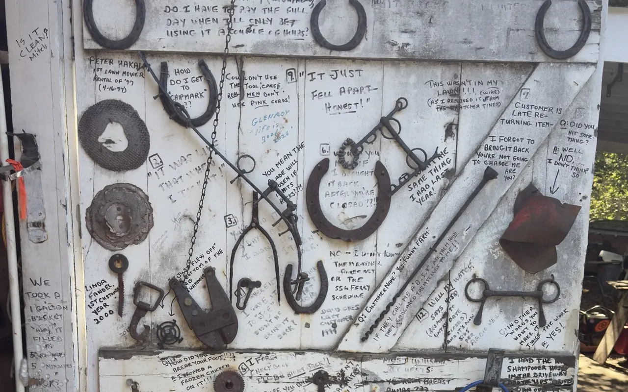 A white barn door at Tilton tool rental in Vineyard Haven covered in horseshoes, old tools and hand-written customer questions