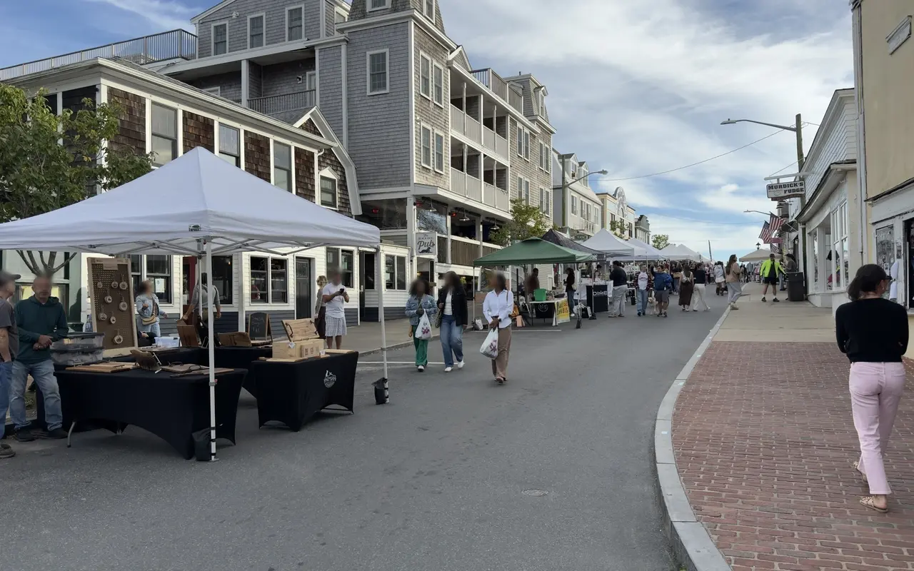 Craft vendor tables under a tent on Circuit Avenue near the Black Dog Pub, shoppers walking past