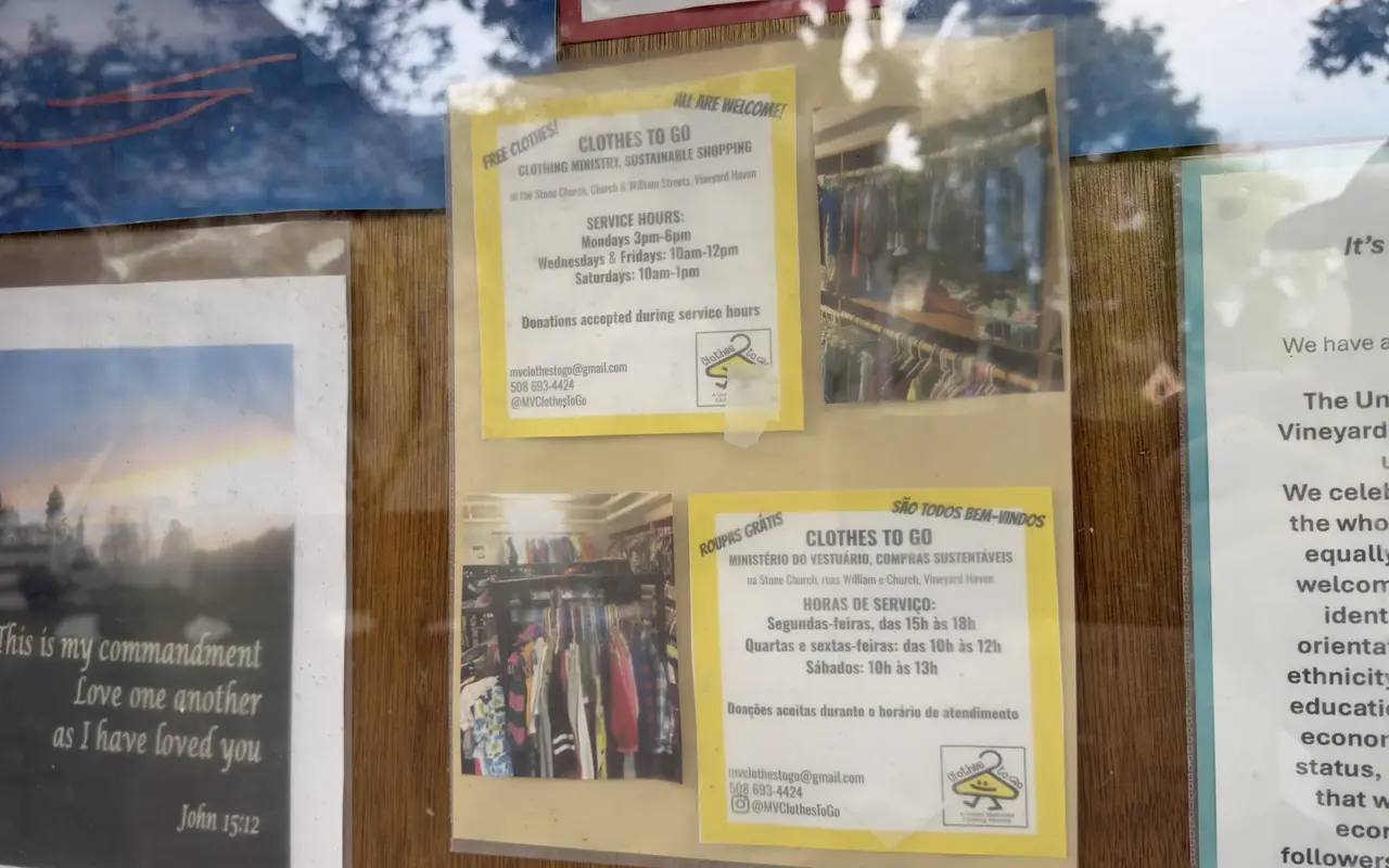 Church notice board with Clothes to Go flyers in English and Portuguese listing free clothing hours