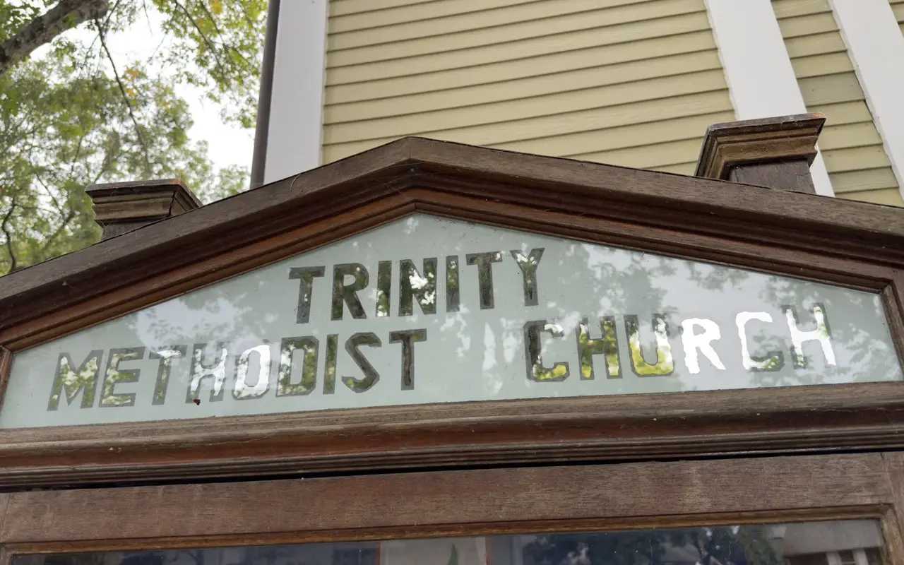 Old wooden sign board reading Trinity Methodist Church in Oak Bluffs