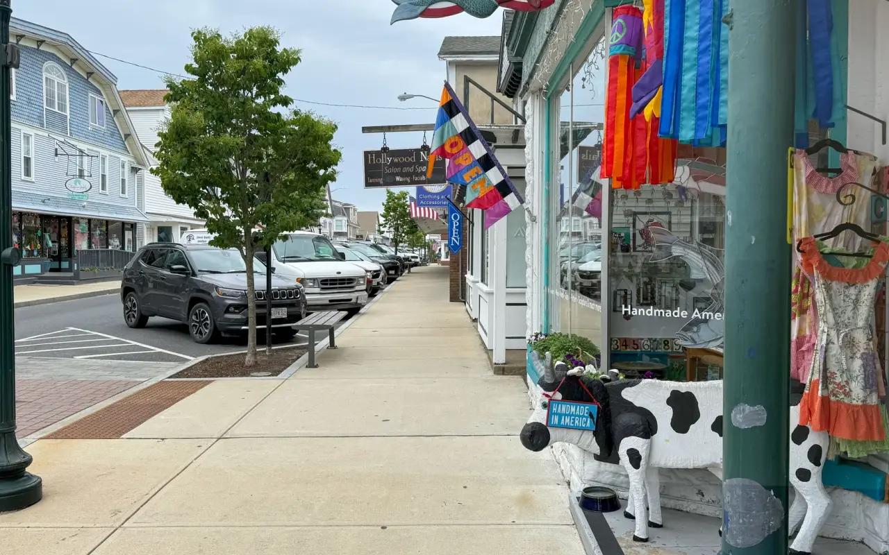 Upper Circuit Avenue in Oak Bluffs with shop fronts, a wooden cow figure and parked cars under trees