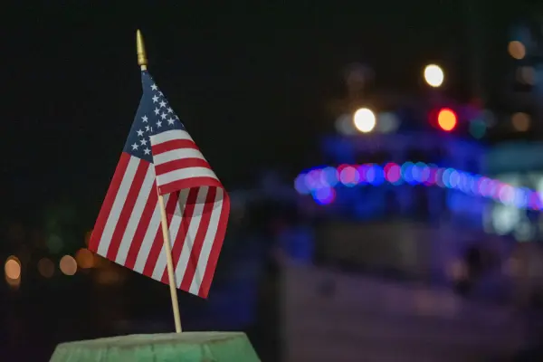 A small American flag against harbor lights at night, Edgartown Fourth of July