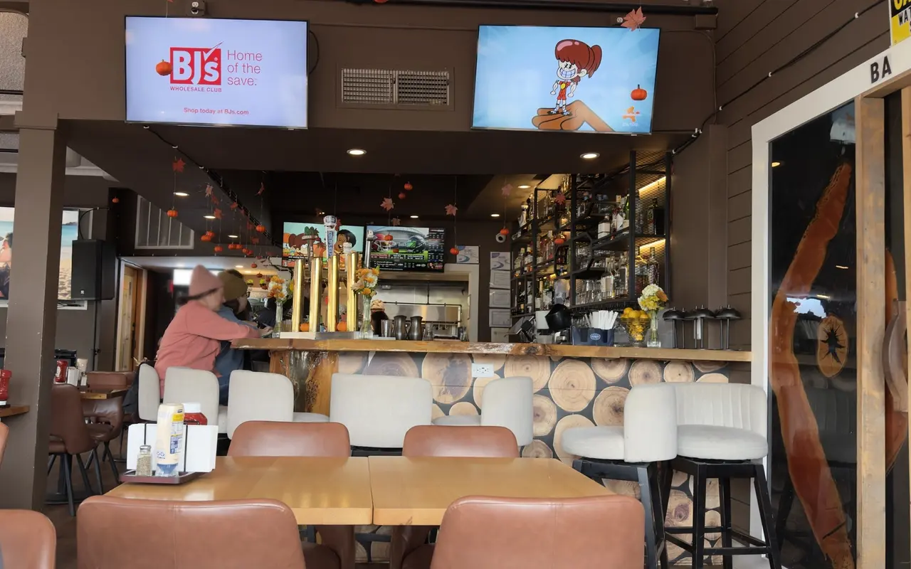 Bar room at the Vineyard Grill in Vineyard Haven, a bar faced with log ends, cream stools, pumpkins and paper leaves hanging from the ceiling