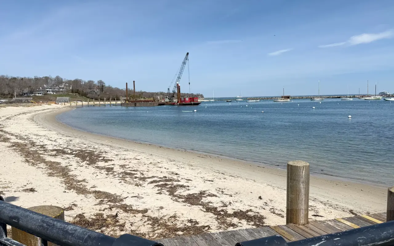 A curved beach on Vineyard Haven harbor with a crane barge in the water