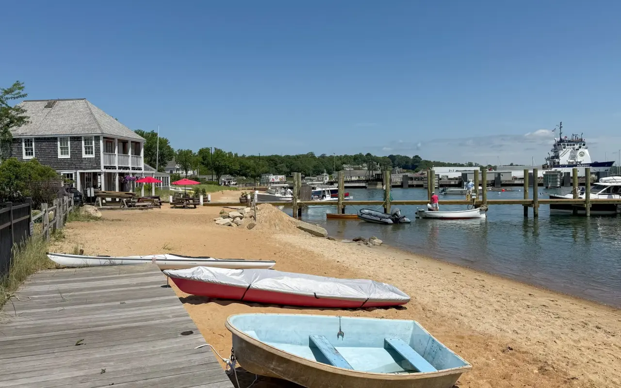 Small boats pulled up on the sand beside a wooden pier on Vineyard Haven harbor