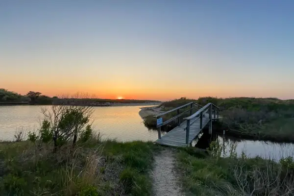 Wooden footbridge over a tidal creek at sunset