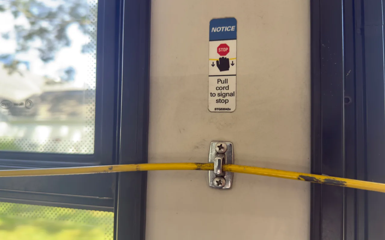Yellow pull cord and stop request sign inside a VTA bus