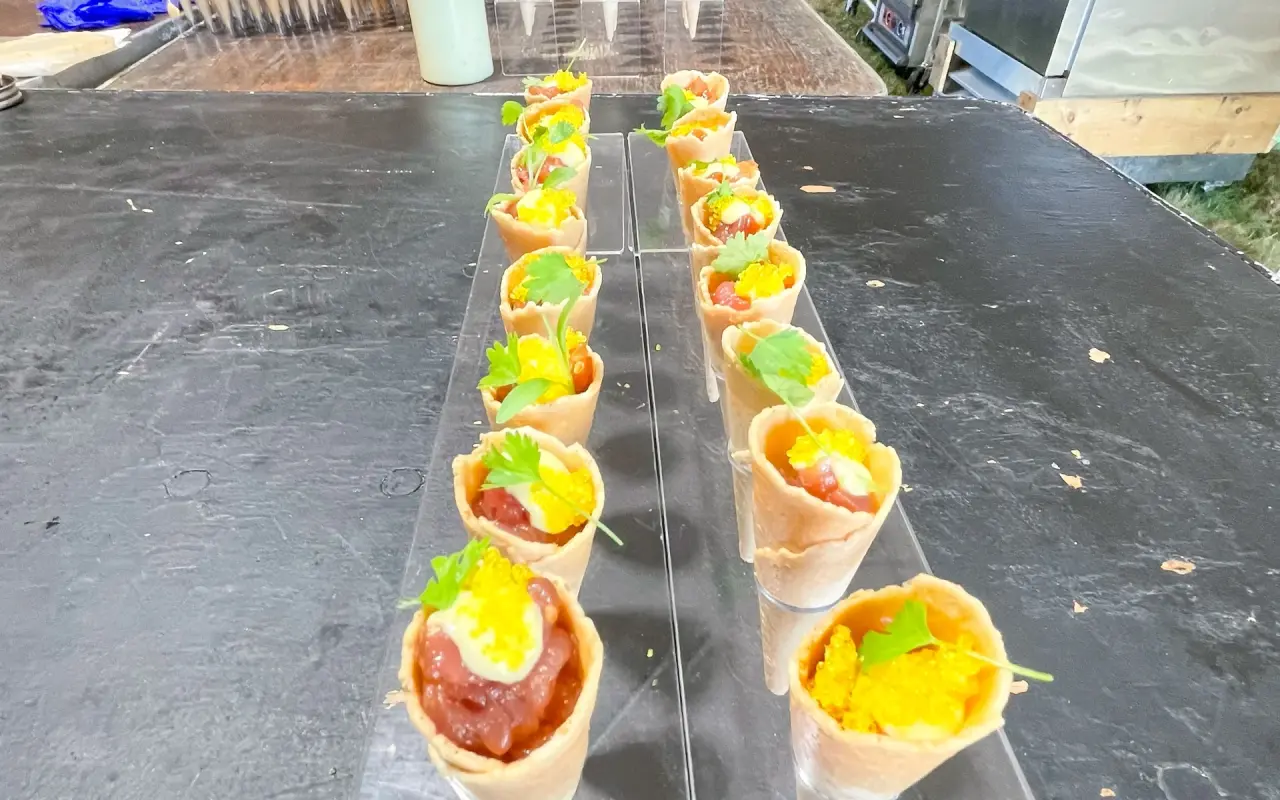 A tray of small appetizer cones lined up on a serving board at a reception