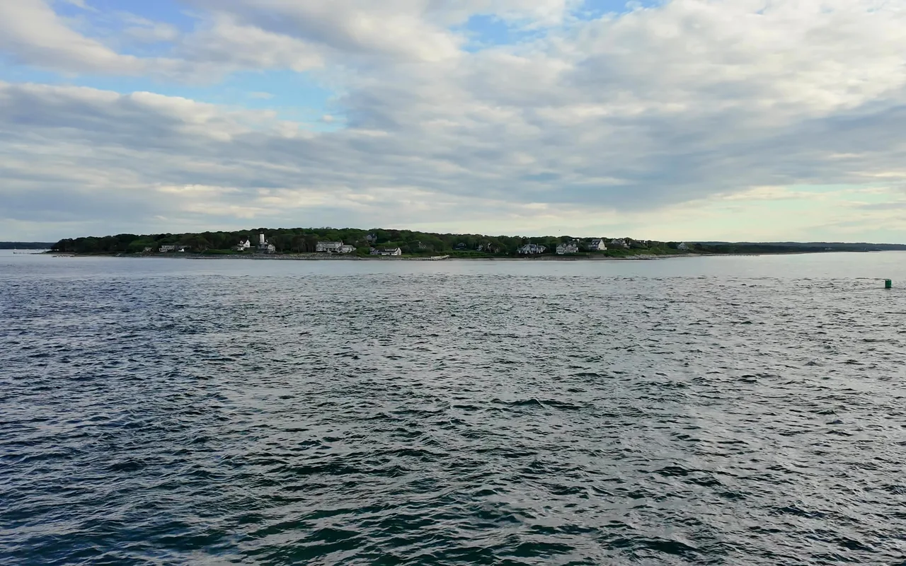 West Chop headland with a white lighthouse and houses seen across the water from a ferry