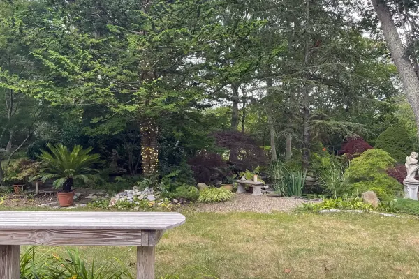 Landscaped garden with stone bench, statue and ornamental plantings