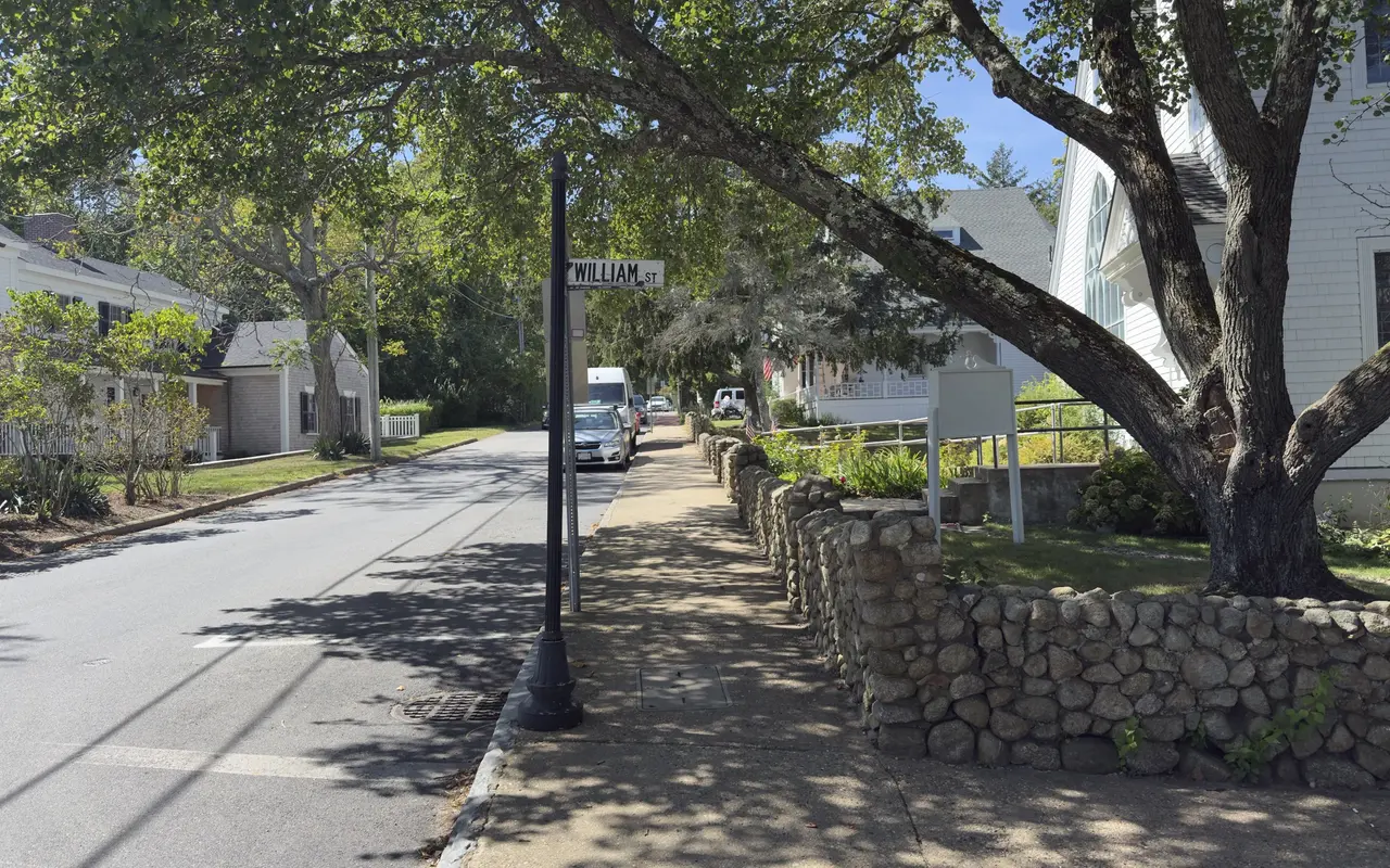 William Street in Vineyard Haven under old shade trees: a fieldstone wall, a white church with an arched window, shingled houses and the street sign
