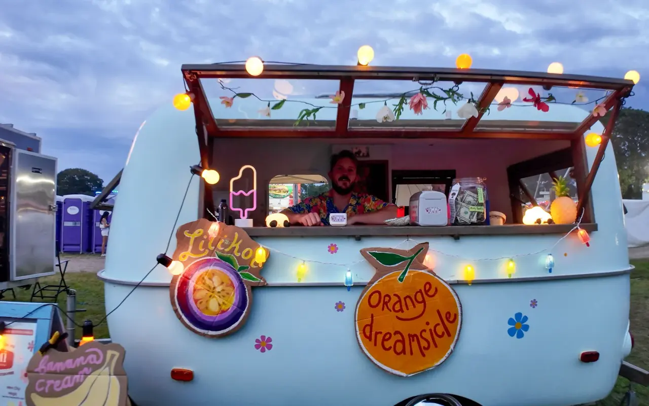 A decorated vintage trailer serving ice cream under string lights at the Martha's Vineyard Agricultural Fair at night