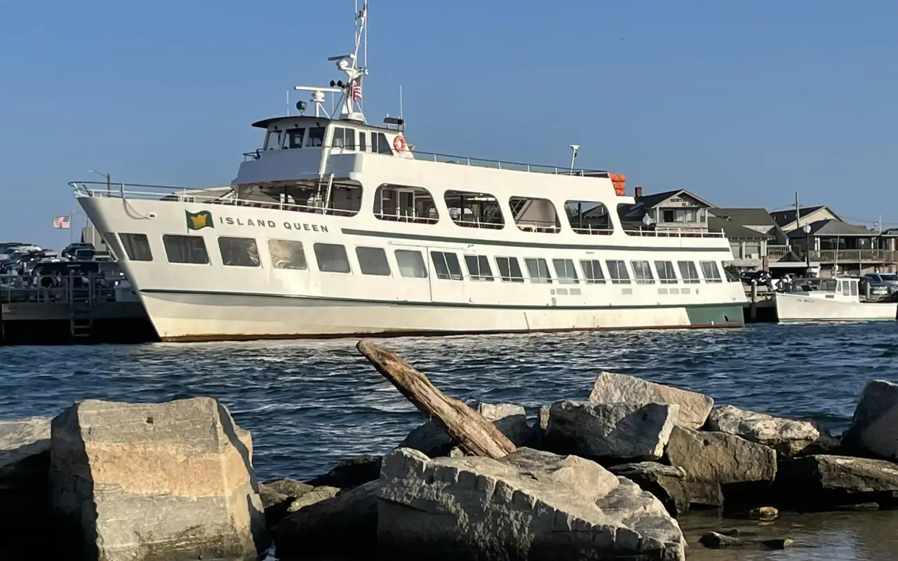 The Island Queen passenger ferry entering Oak Bluffs harbor past large jetty rocks