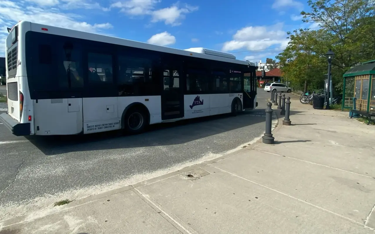 A white VTA bus stopped at a bus stop beside a brick sidewalk in Vineyard Haven