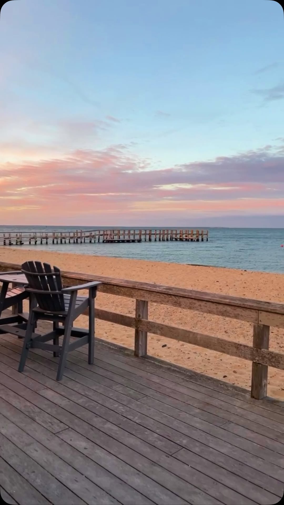 Pink sky over the water at the East Chop Beach Club in Oak Bluffs, with Adirondack chairs on the dec...