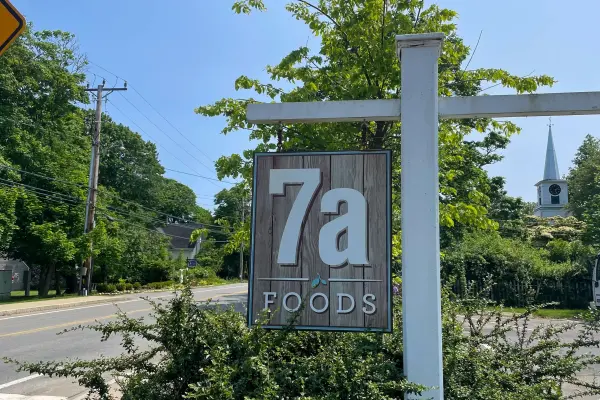 7a Foods sign in West Tisbury with a church steeple behind