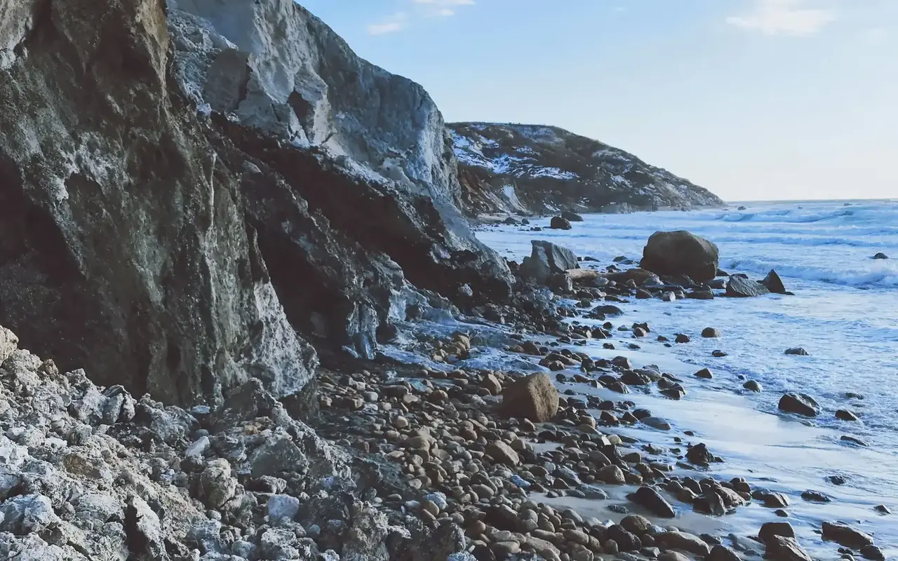 Boulders and the gray clay cliff face at Moshup Beach on an overcast day