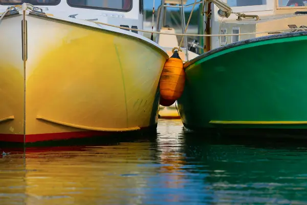 Colorful fishing boat bows with an orange fender between them