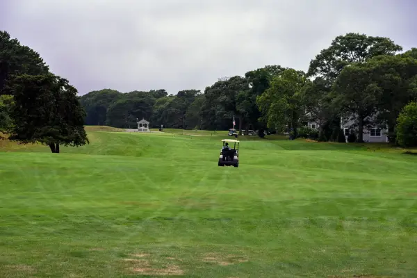 Golf cart heading down a wide green fairway