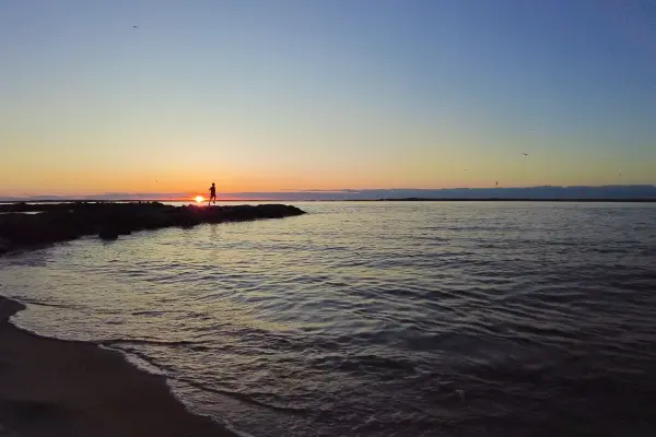 Silhouetted figure on the jetty at sunset