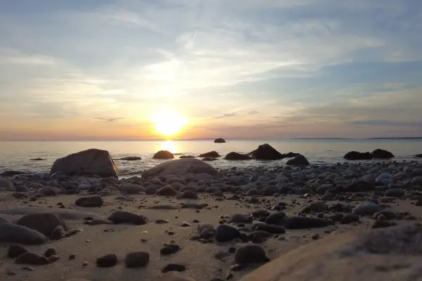 Sun setting over the water from a rocky West Tisbury beach